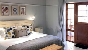 A bedroom with a bed, bedside table, and a window with curtains. - Oyster Bay Lodge (Oyster Bay)