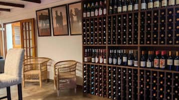 Una cava de vinos con varias estanterías, sillas de mimbre y obras de arte enmarcadas en la pared.