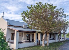 A single-story building with a flat roof, a covered porch area, and a tree in front. - Oyster Bay Lodge (Oyster Bay)