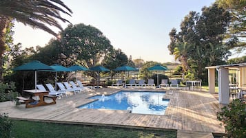 Una piscina al aire libre, sombrillas, tumbonas