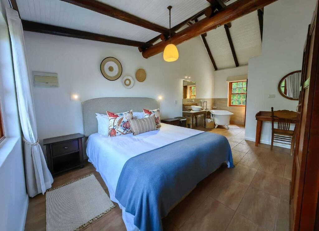 Un dormitorio con una cama grande, techo de madera y un baño visible al fondo.