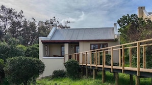 A house with a wooden deck, surrounded by greenery and trees.