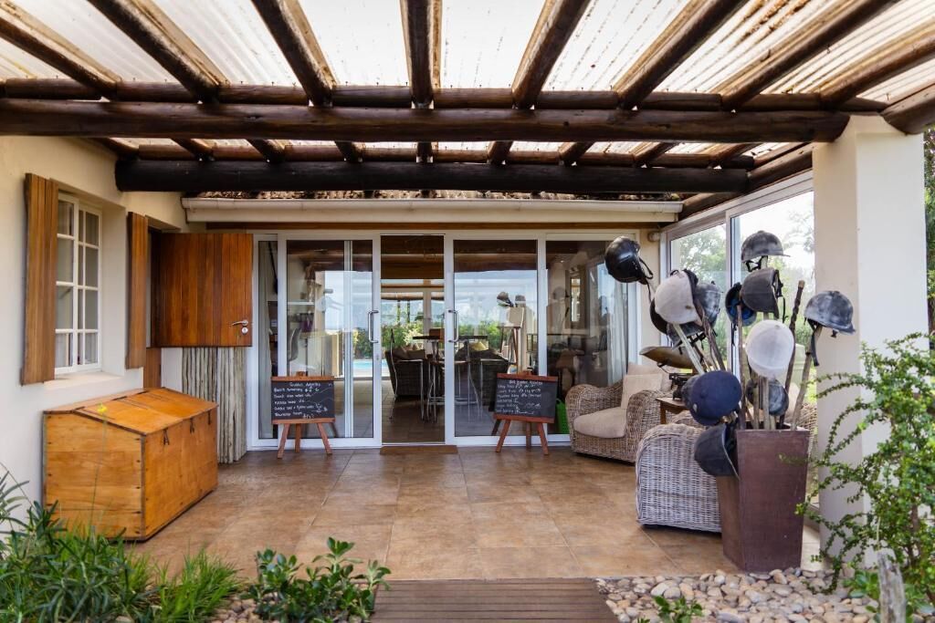 A covered patio area with a wooden ceiling, wicker furniture, and a rustic wooden chest.