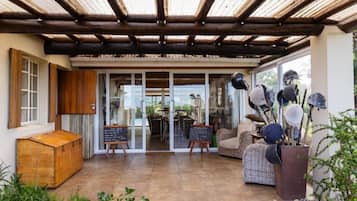 A covered patio area with a wooden ceiling, wicker furniture, and a rustic wooden chest.