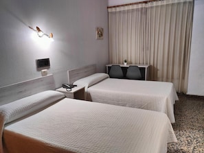 A hotel room with two beds, a desk, a chair, a phone, and a window with curtains.