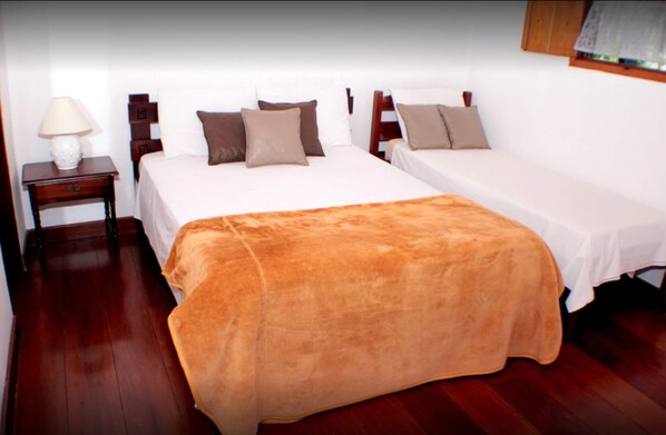 Une chambre d’hôtel avec deux lits, une table de chevet avec une lampe et un plancher en bois.