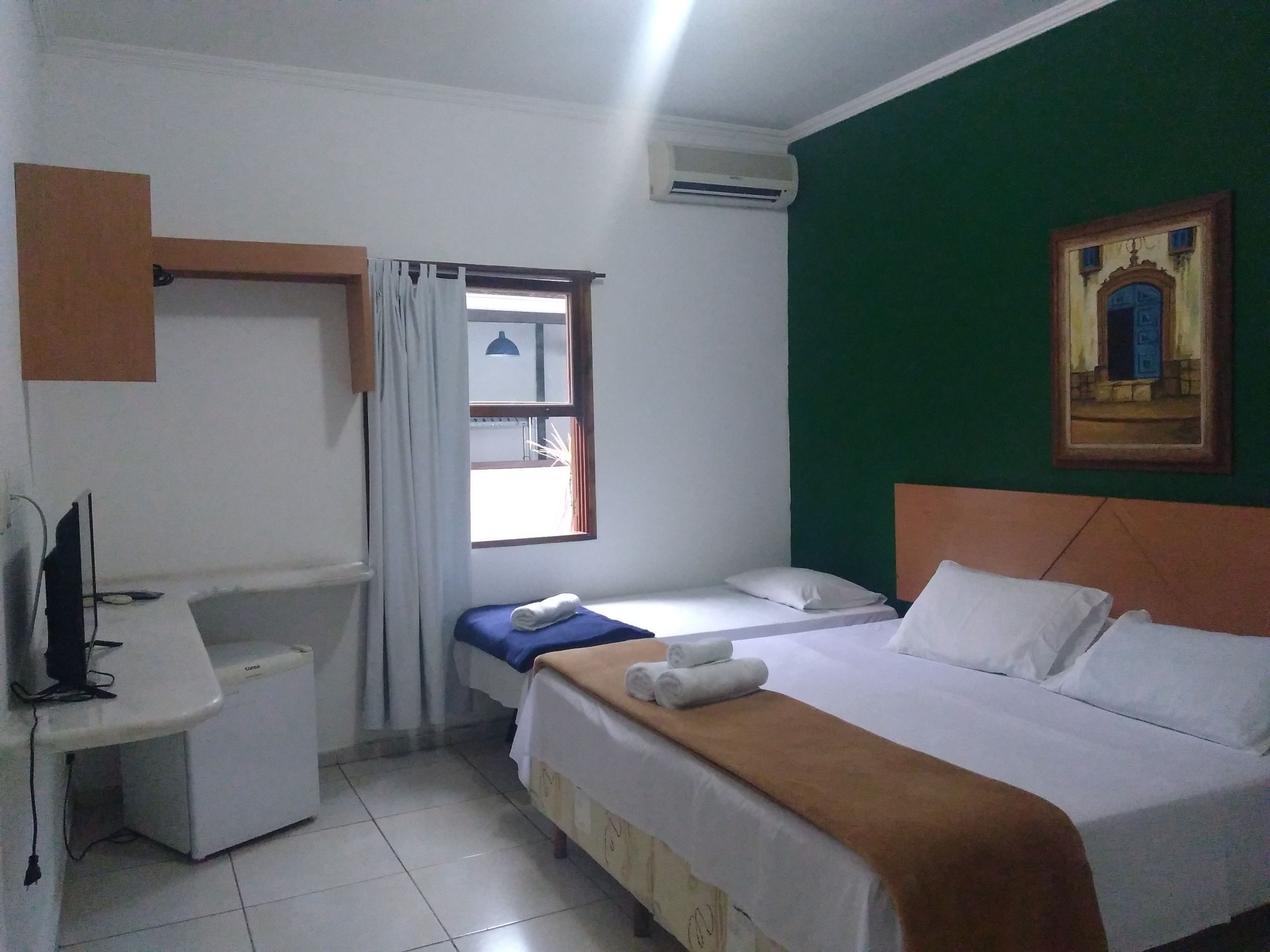 A small, clean room with a bed, a desk, and a window.