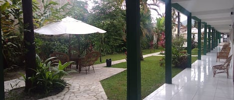 A covered outdoor area with a stone pathway, wicker furniture, and a white umbrella.