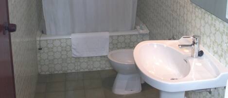 Une salle de bain avec un rideau de douche, des toilettes et un lavabo.