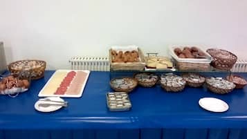 A buffet table with various food items, including pastries and desserts, arranged on a blue tablecloth.