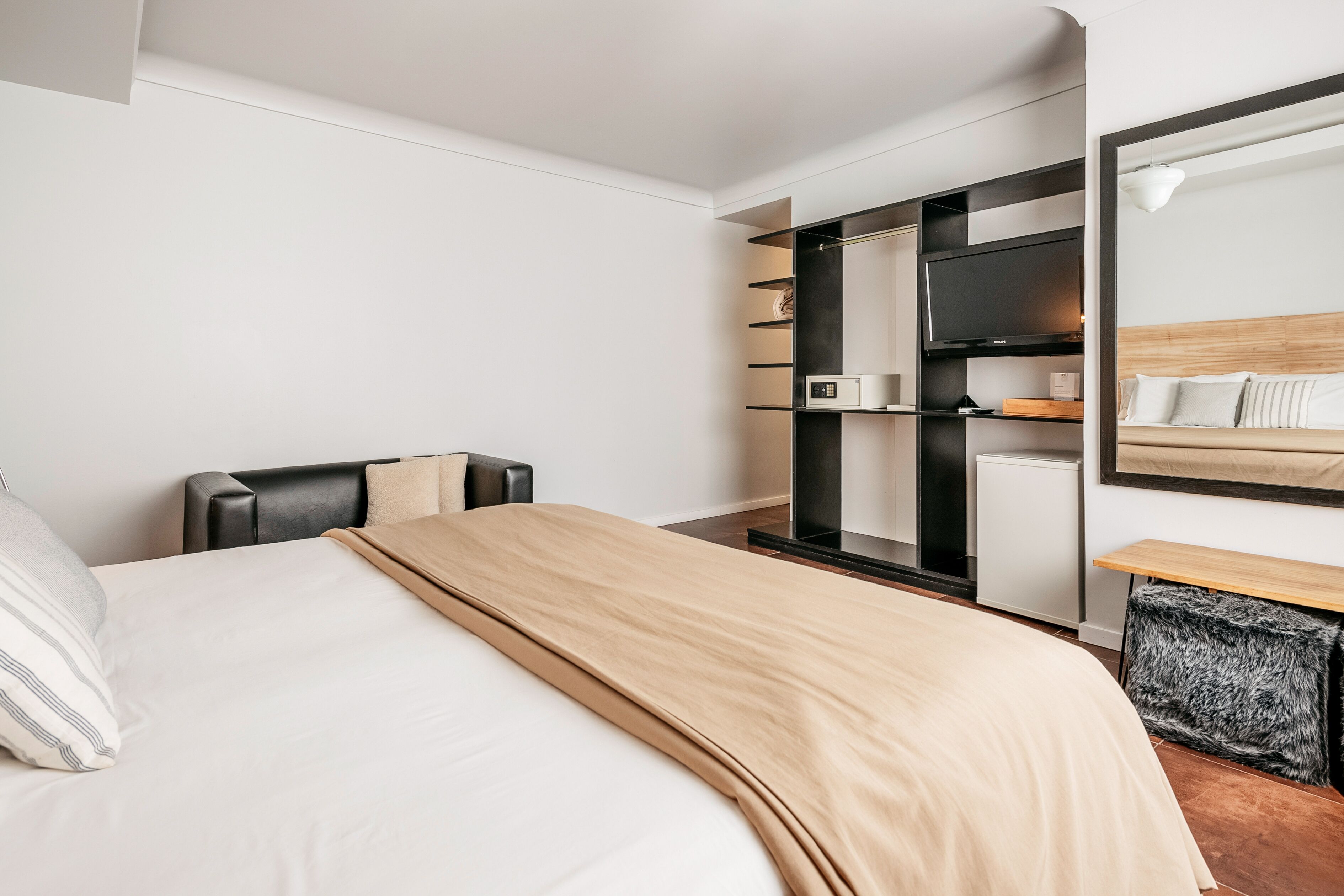 Une chambre d’hôtel moderne équipée d’un lit, d’un coin salon avec une table, d’une télévision et d’une armoire.