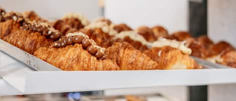 A bakery display with various baked goods including croissants and sandwiches.