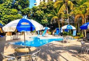 Una piscina al aire libre, sombrillas, sillones reclinables de piscina