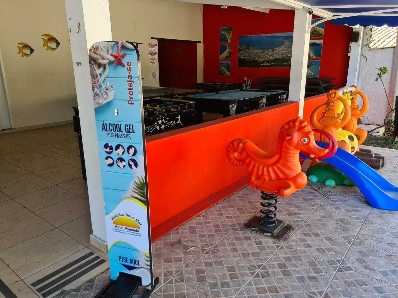 Un espace de jeux pour enfants comprenant une table de billard, un toboggan et une sculpture colorée.