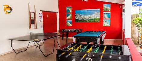 Een kamer met een tafelvoetbaltafel, een pingpongtafel en een pooltafel.