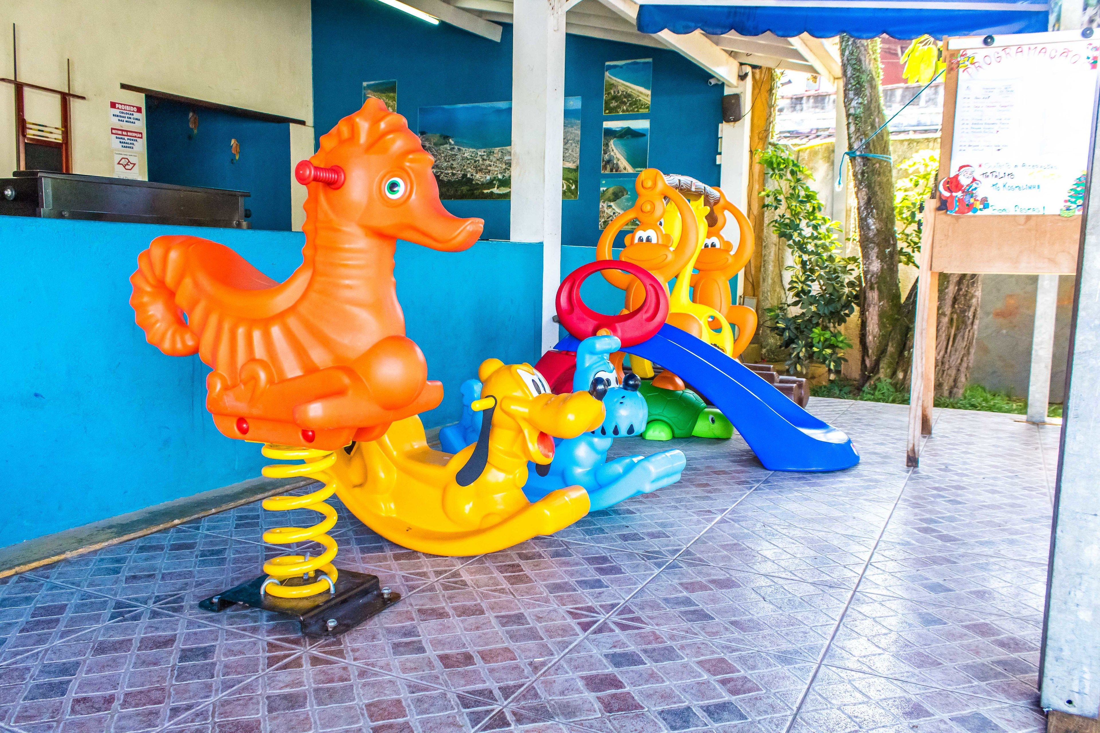 A children's play area with a seahorse ride, a slide, and a ring toss game.