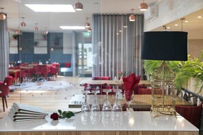 Un comedor moderno con mostrador de mármol, copas de vino y una lámpara decorativa.