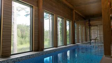 An indoor swimming pool with wooden walls and large windows.