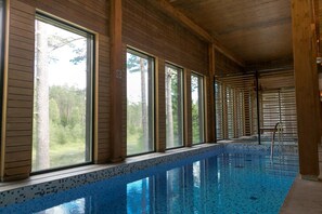 Una piscina interior con paredes de madera y ventanas amplias.