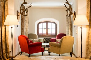 Una habitación con dos sillones, una mesita y una ventana con cortinas.
