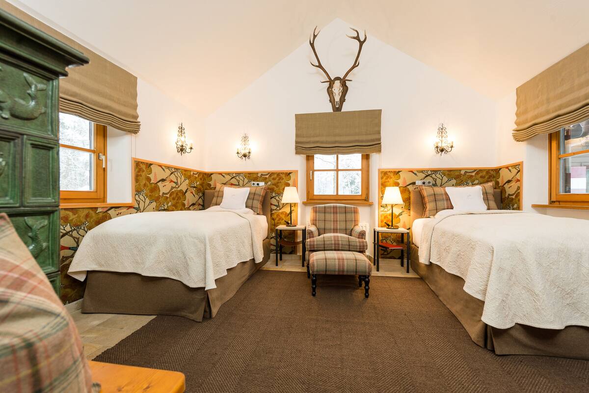 A room with two beds, a chair, and a deer head mounted on the wall.
