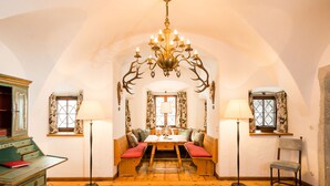 A cozy room with a wooden bench seating area, a chandelier, and a table with lamps. - Schloss Prielau Hotel & Restaurants (Zell am See)