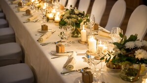 A long banquet table set for a formal event with white chairs, candles, and floral centerpieces. - Schloss Prielau Hotel & Restaurants (Zell am See)