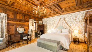 A bedroom with a large bed, a wooden ceiling, a chandelier, and a floral wallpaper. - Schloss Prielau Hotel & Restaurants (Zell am See)