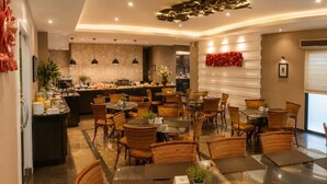 A hotel dining area with wicker chairs, glass tables, a buffet counter, and pendant lighting. - Spazzio Hotel Residence (Fortaleza)