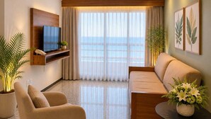 A modern living room with a sofa, armchair, TV, and potted plants. - Spazzio Hotel Residence (Fortaleza)