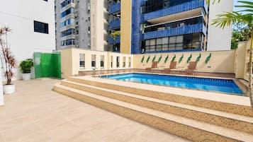 Una piscina al aire libre, sillones reclinables de piscina