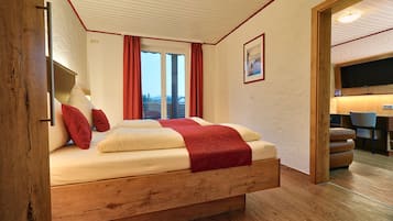 Un dormitorio con cama de madera, cortinas rojas, un cuadro en la pared y vistas al exterior.