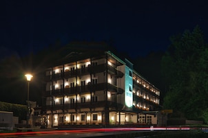 Un hotel de varios pisos con balcones, una entrada visible y un letrero que indica el nombre 'Harras'.