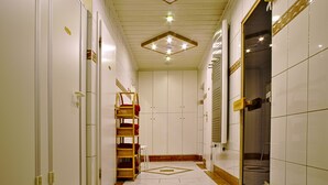 Un couloir d’hôtel aux murs blancs, au sol carrelé et doté d’un luminaire central.