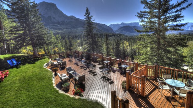 A deck with outdoor seating and a view of mountains. - Overlander Mountain Lodge (Jasper East)