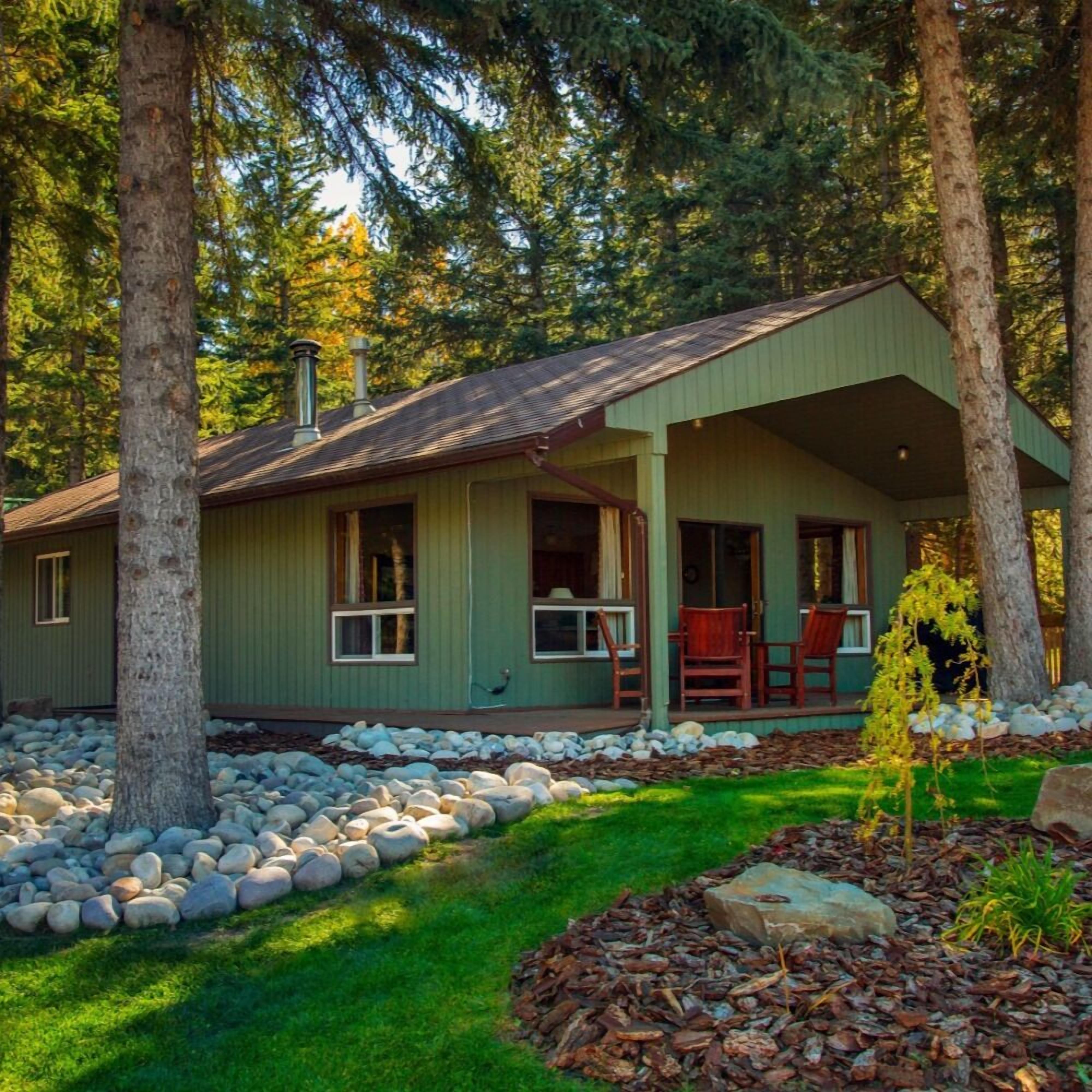 A cabin with a porch, stone pathway, and surrounding trees.