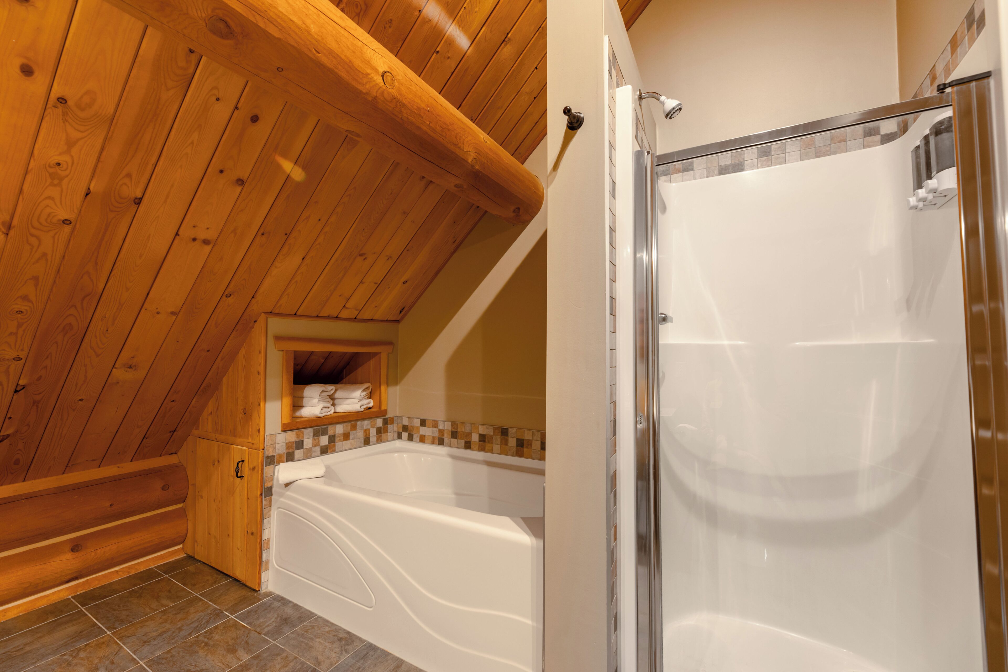 A bathroom with a wooden ceiling, a bathtub, and a shower enclosure.