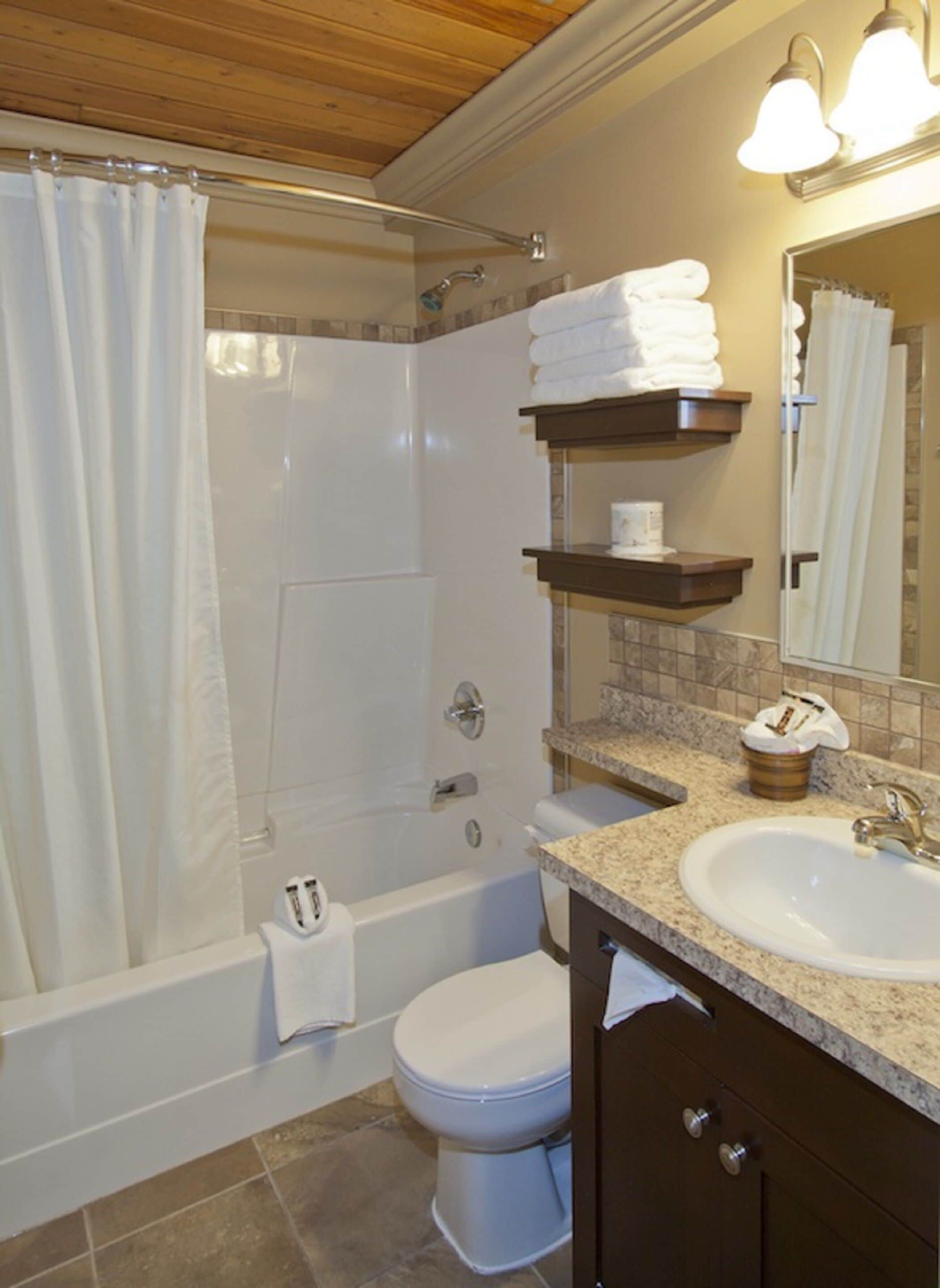 Un baño con ducha, inodoro, lavamanos y toallero.