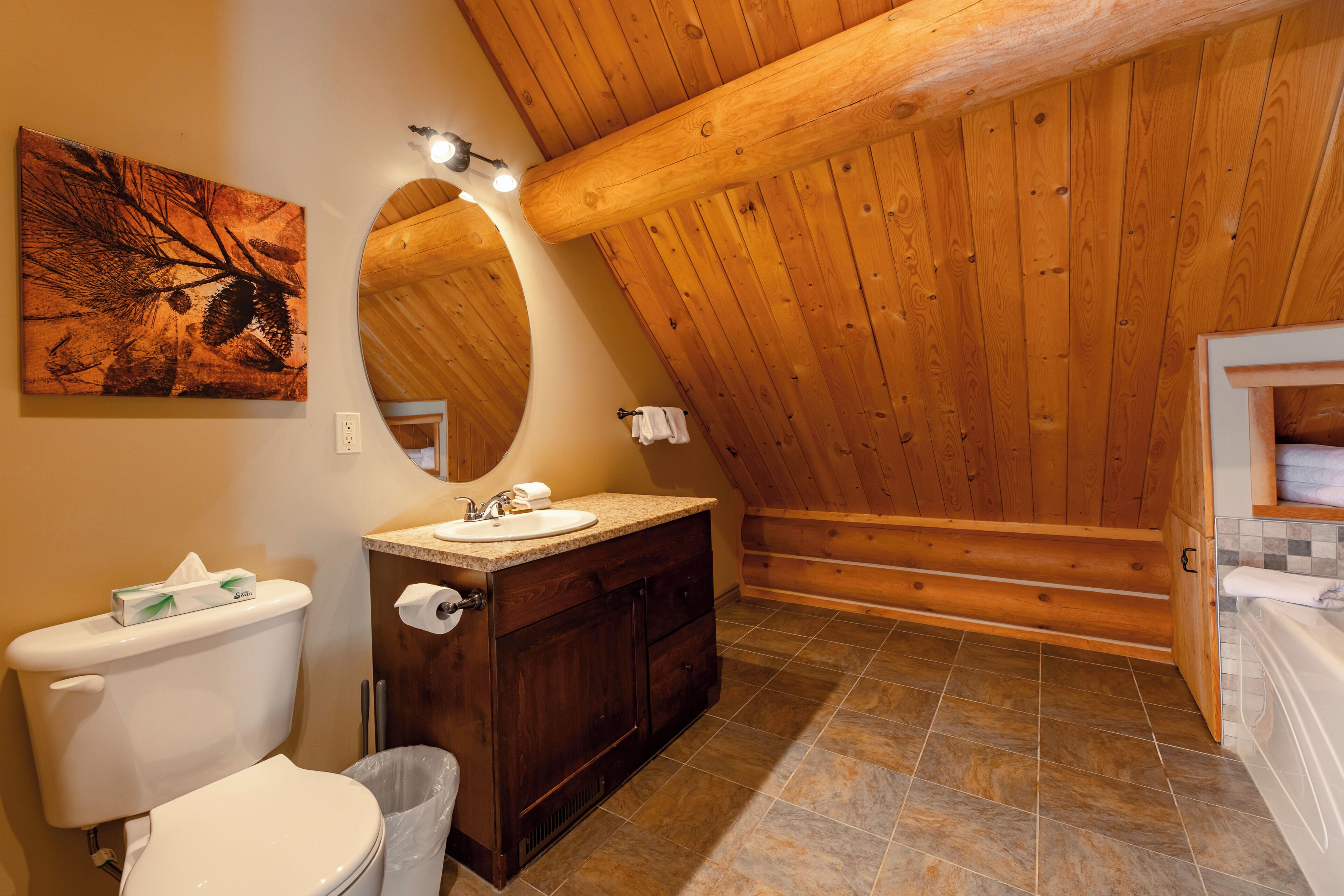 A bathroom with a wooden ceiling, a sink, a toilet, and a mirror.