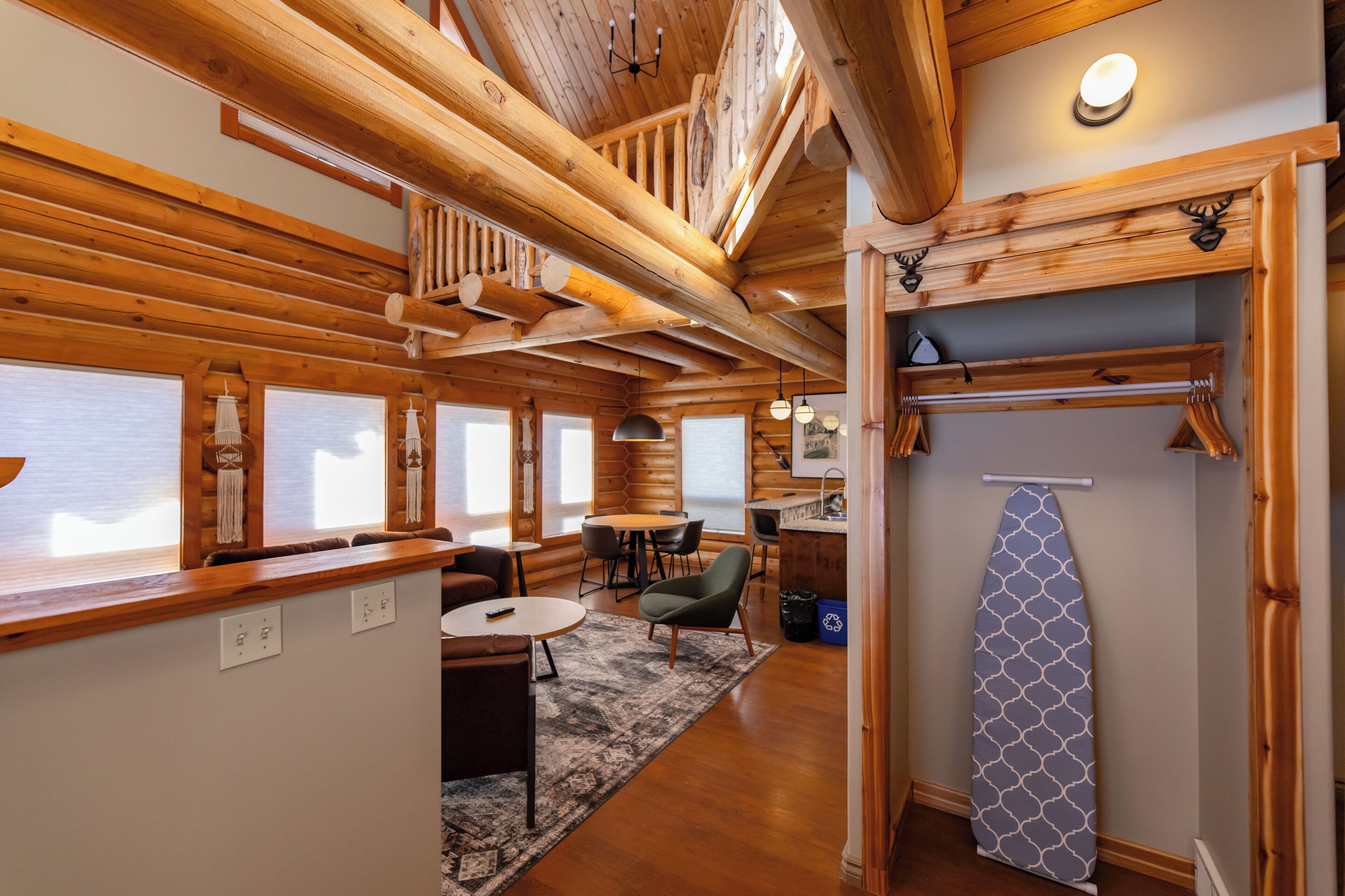 A log cabin interior with a dining area, a kitchen, and a loft space.