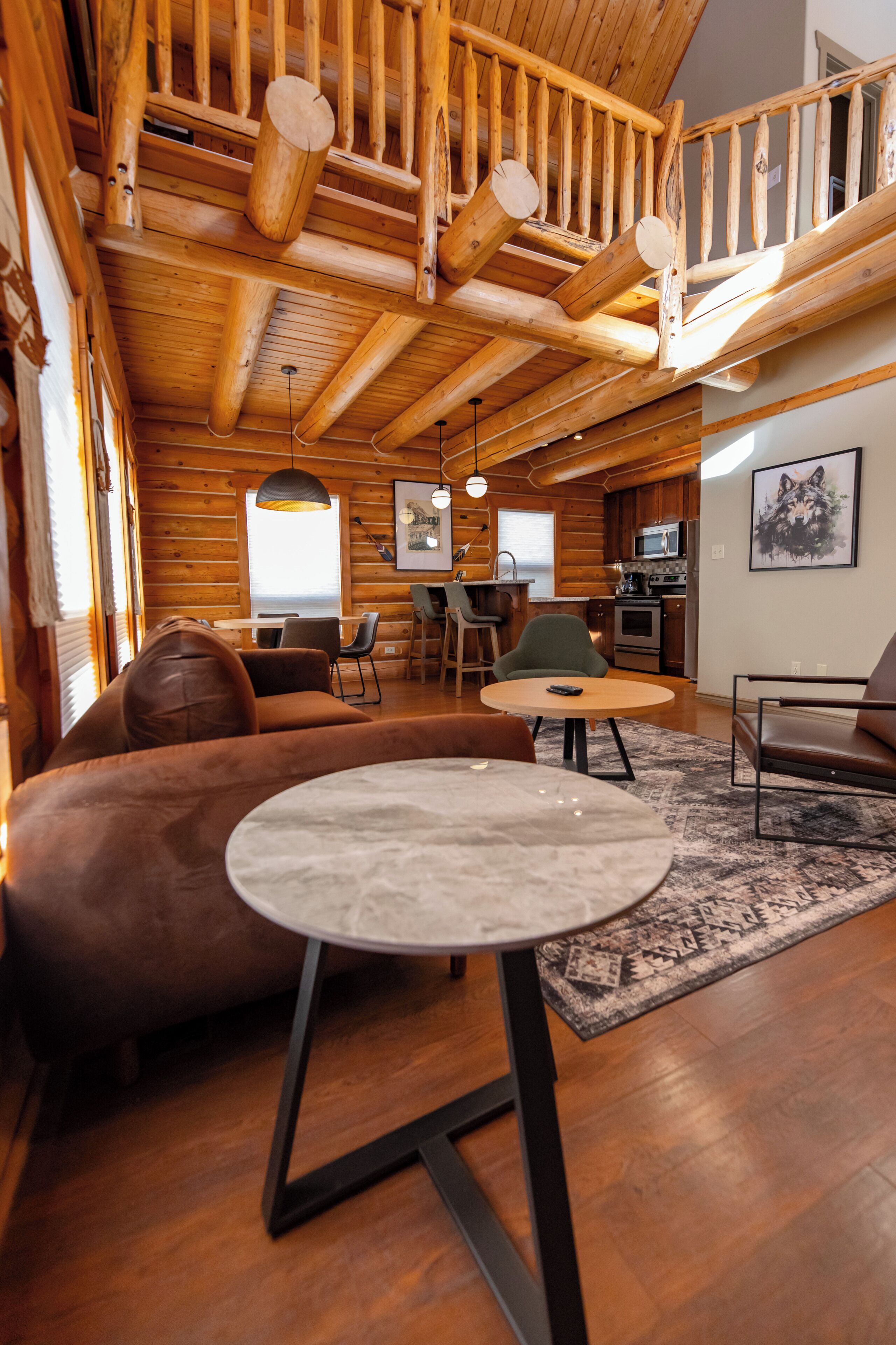 A wooden interior with a sofa, round table, and a staircase.