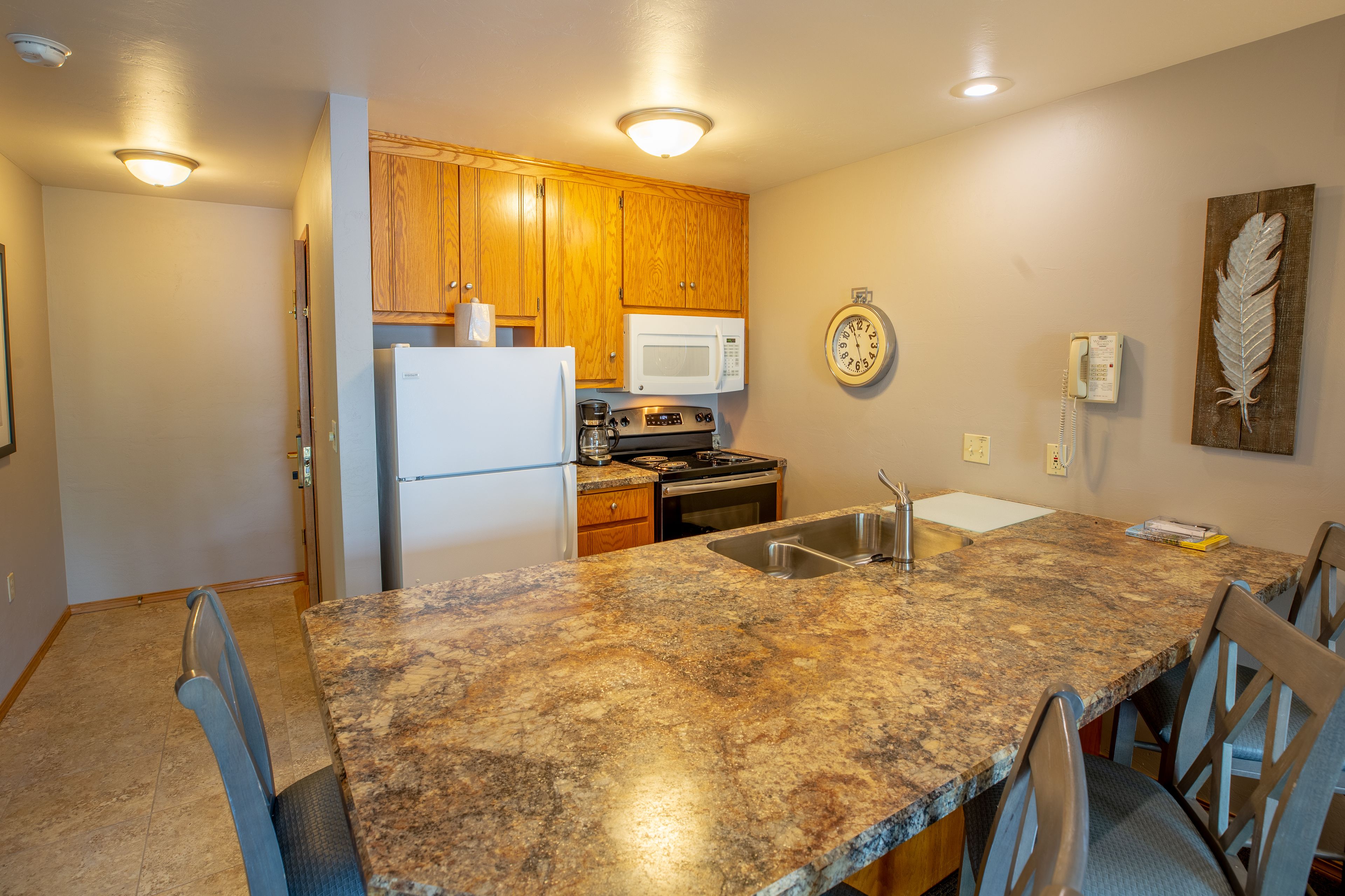 A kitchen with wooden cabinets, a white refrigerator, a microwave, a stove, and a sink.