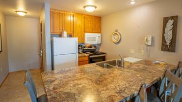 A kitchen with wooden cabinets, a white refrigerator, a microwave, a stove, and a sink.