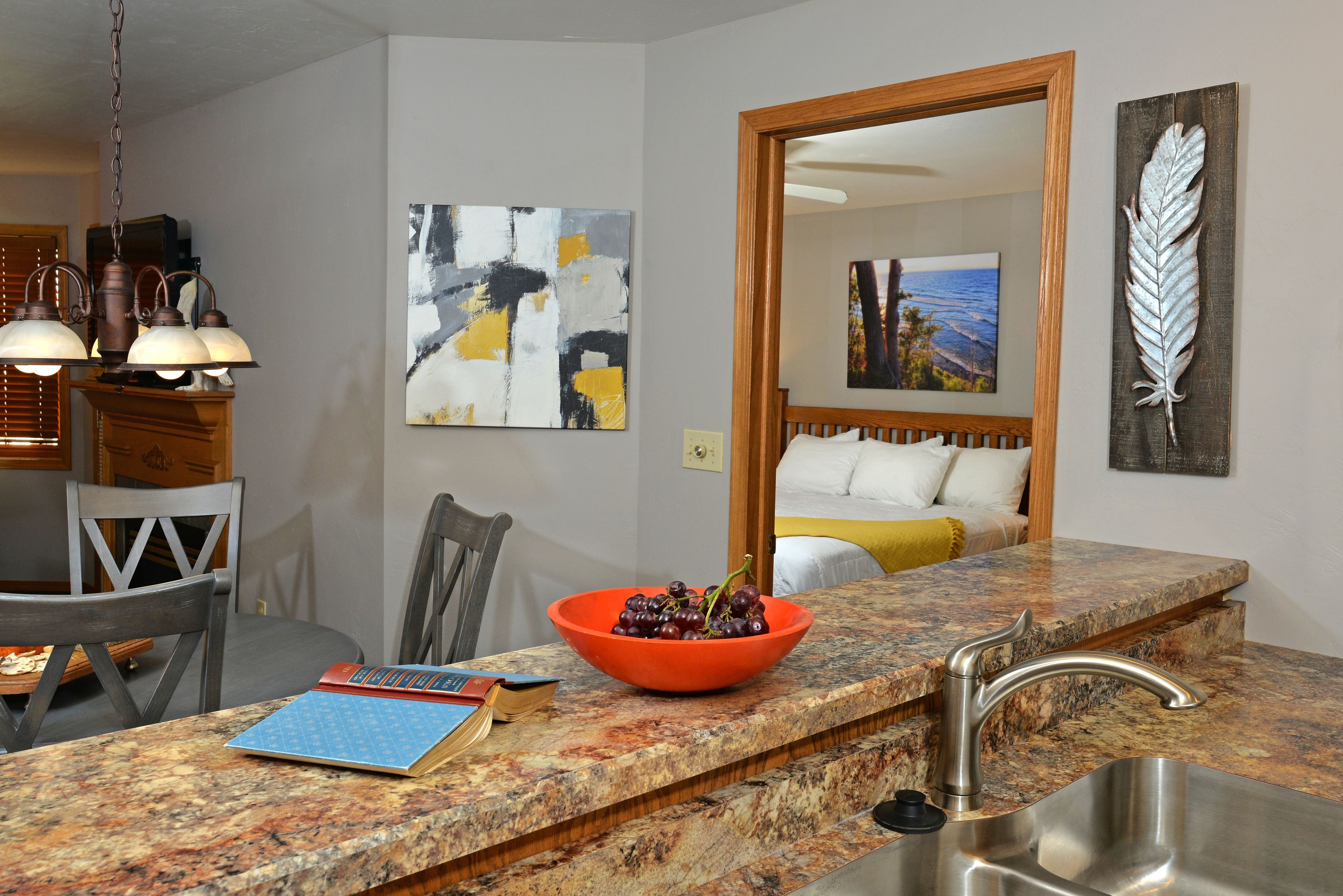 A kitchen with granite countertops, a bowl of red grapes, a notebook, and a smartphone on the counter.
