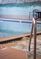 Un jacuzzi con borde de azulejos y barandilla de metal.