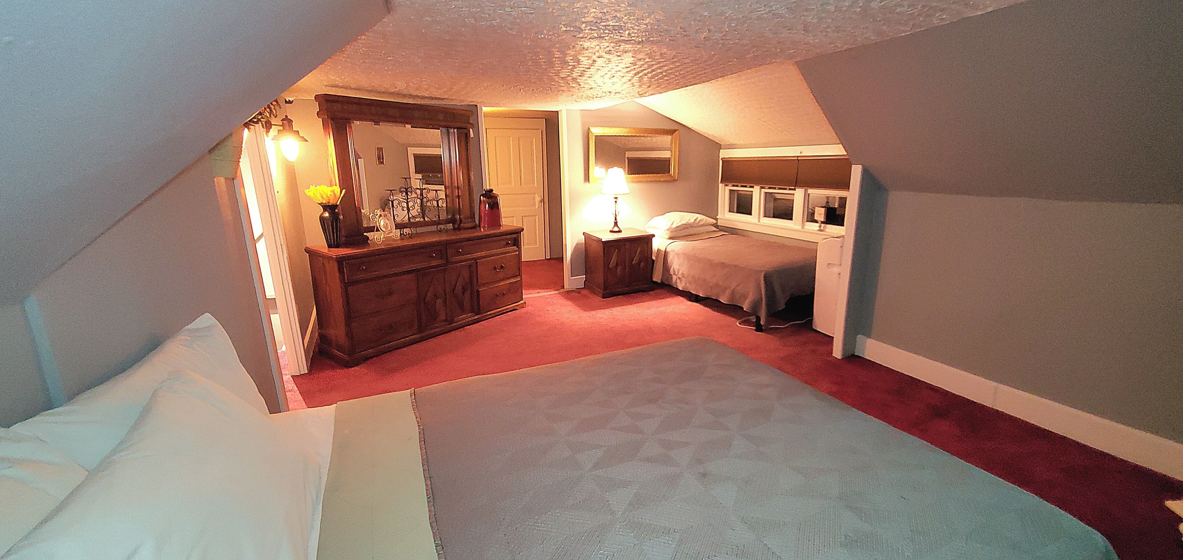 A bedroom with a bed, dresser, and a desk with a lamp.