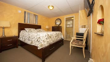 Un dormitorio con una cama, mesitas de noche, una silla, un espejo y un televisor montado en la pared.
