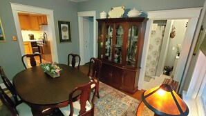 A dining room with a wooden table, chairs, a cabinet, and a lit floor lamp. - Simmons Motel (Hershey)