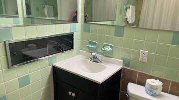 A bathroom with a white sink, black cabinet, and a toilet. There is a mirror above the sink and a shower curtain in the background.