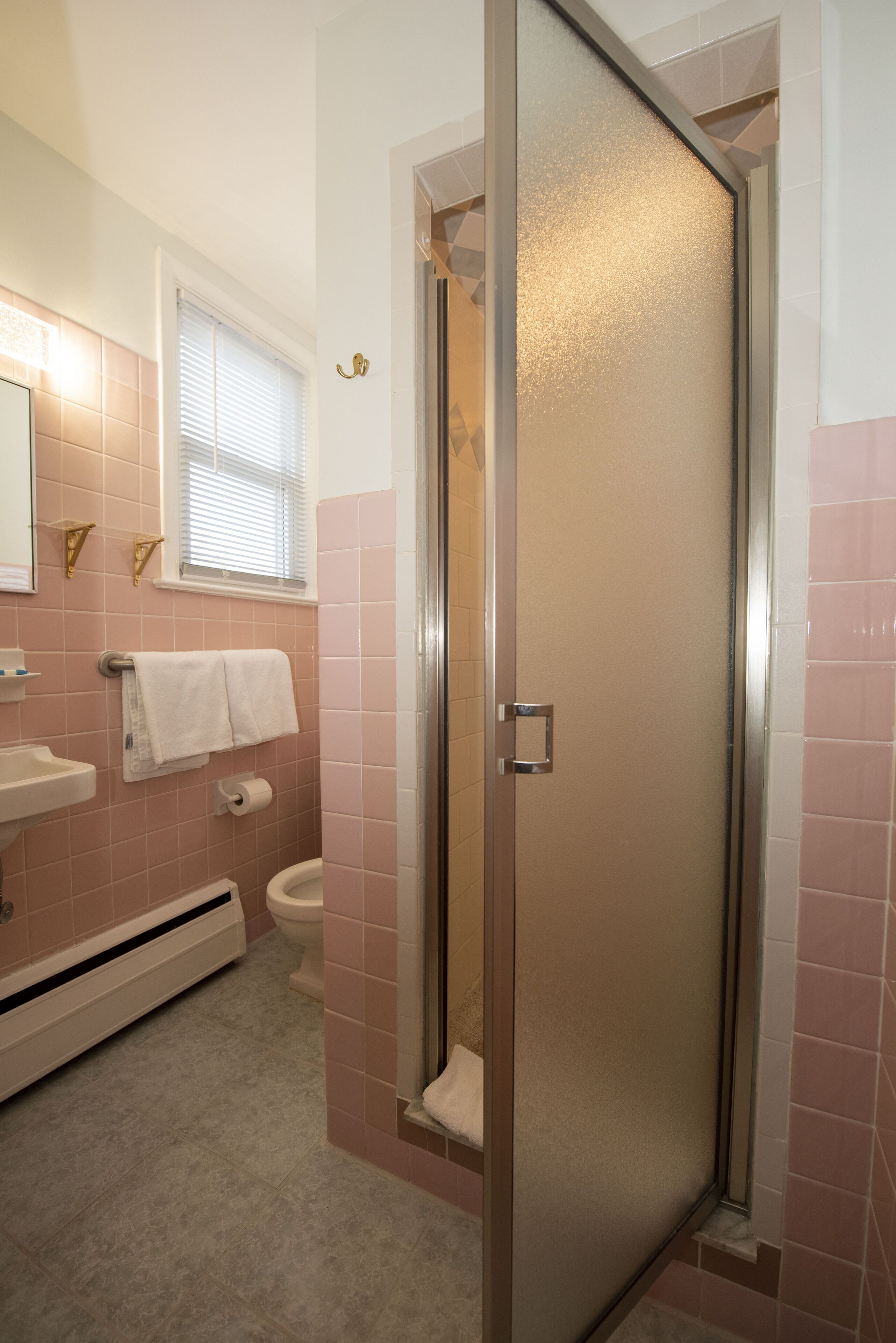 Un baño con ducha, inodoro, lavabo y perchero para toallas.